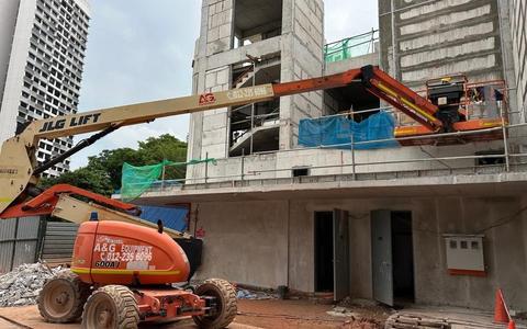JLG 600AJ articulated boom lift reaching up and over a ledge on a construction site in Johor